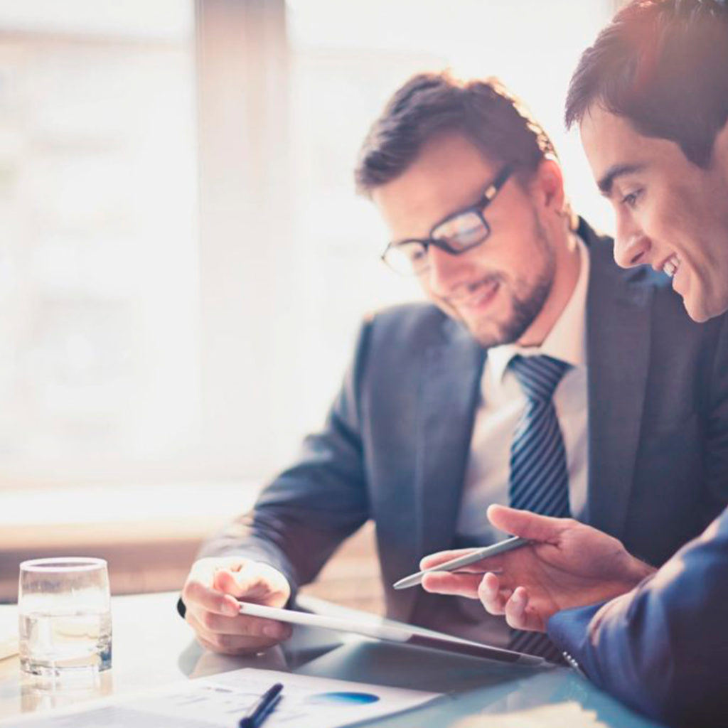 Two men in suits and ties looking at a tablet.