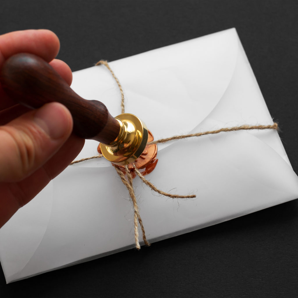 A person is holding a wax seal on top of a letter.