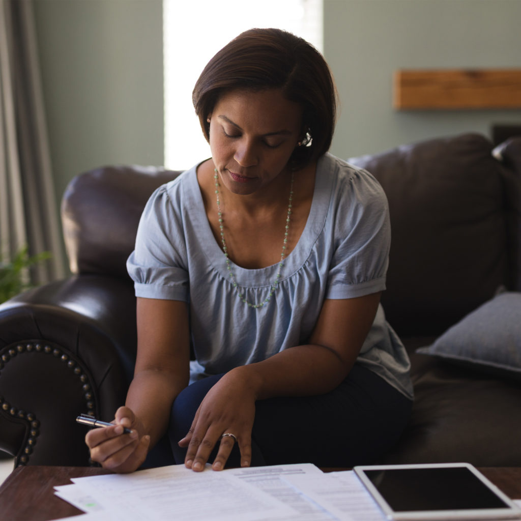 A woman sitting on the couch writing on paper.